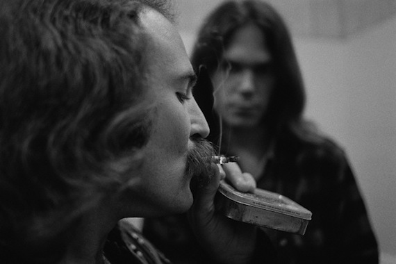 12 Jul 1970, USA --- Musician David Crosby smokes a cigarette while Neil Young looks on. They are in a backstage bathroom. --- Image by © Henry Diltz/CORBIS
